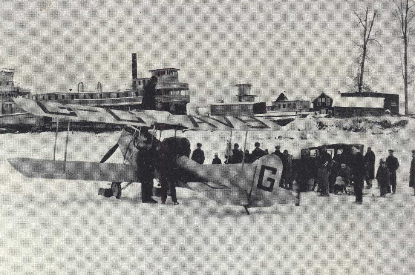 Biplane is greeted by group of people on an icy lake