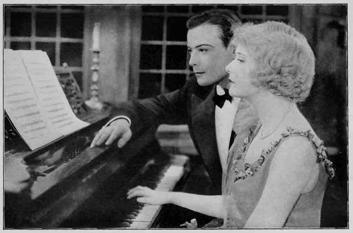 Man and woman sitting at piano while she plays it listlessly.