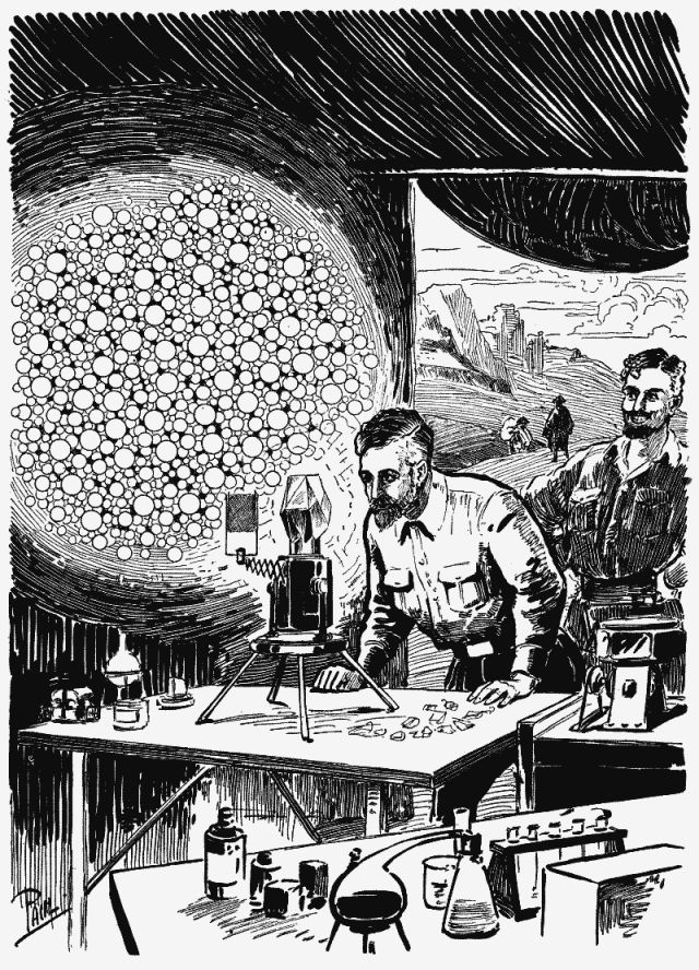 Man gazes into gadget on table while other man looks on.