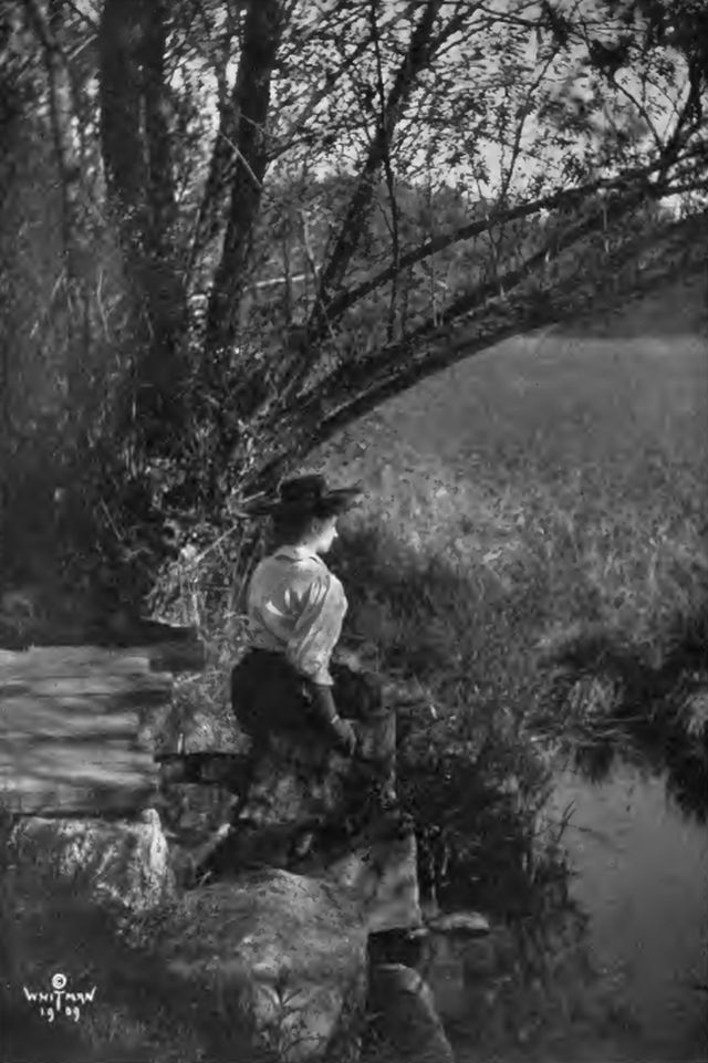 Helen is sitting on a rock looking out over a small body of water
