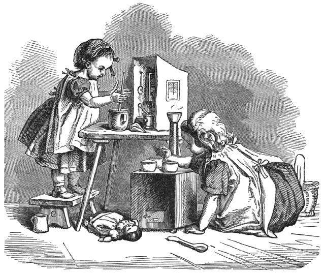 Two girls are cooking in a play kitchen. One girl is standing on a stool and the other girl is sitting on the floor.