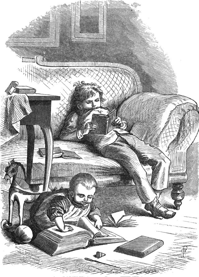 A boy slouches on a sofa reading a book while a small child sits on the floor and turns pages in a book