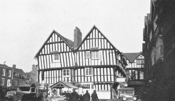 a three-story square wood and plaster building facing a town square