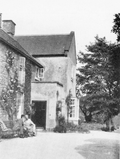 2 men sitting on a bench in front of an inn