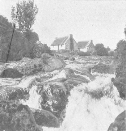 a waterfall with houses behind