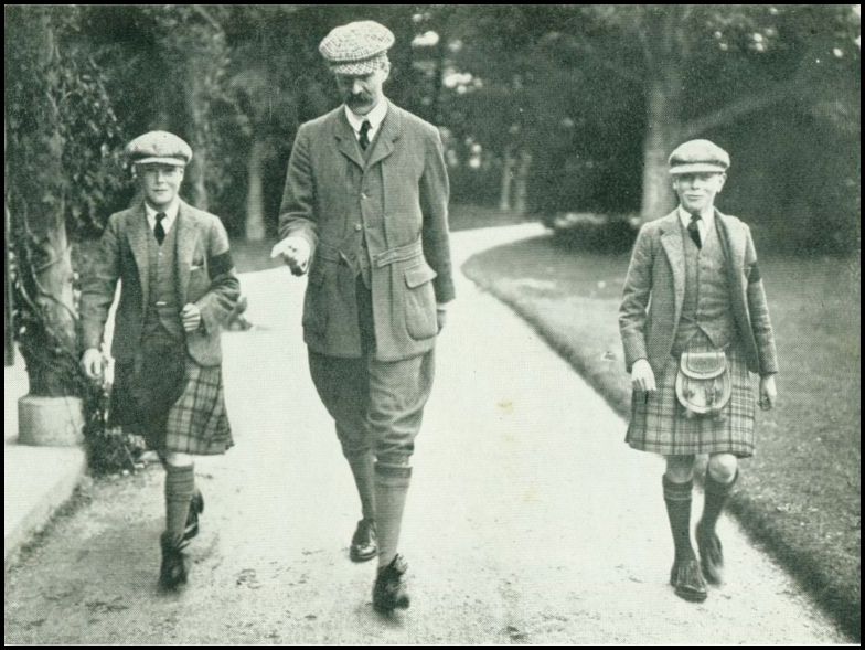 Two boys, wearing kilts, are walkin on either side of an older man.