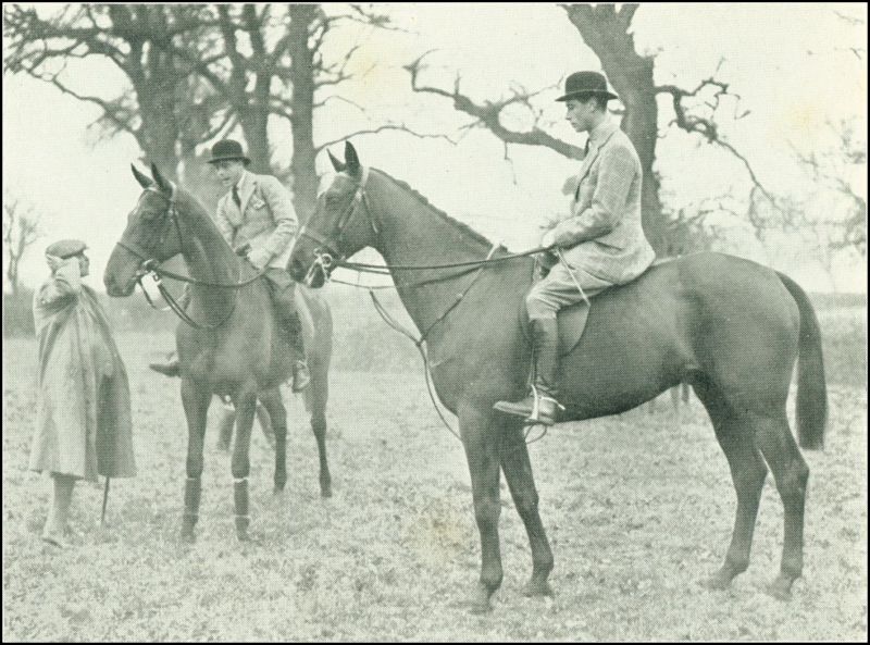 Two men are on horseback and appear to be speaking to another man standing nearby.
