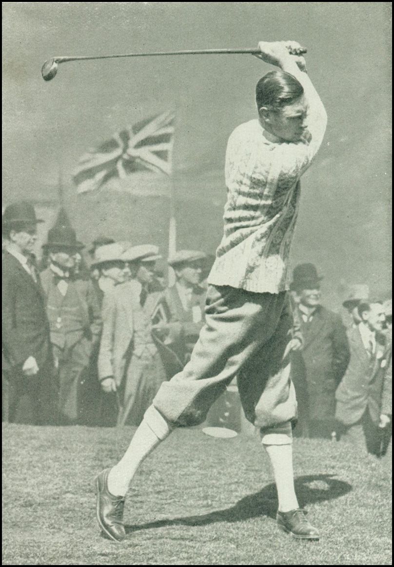 A man wearing golf attire is swinging a golf club in the air. There is a British flag in the background as well as a large number of men watching.