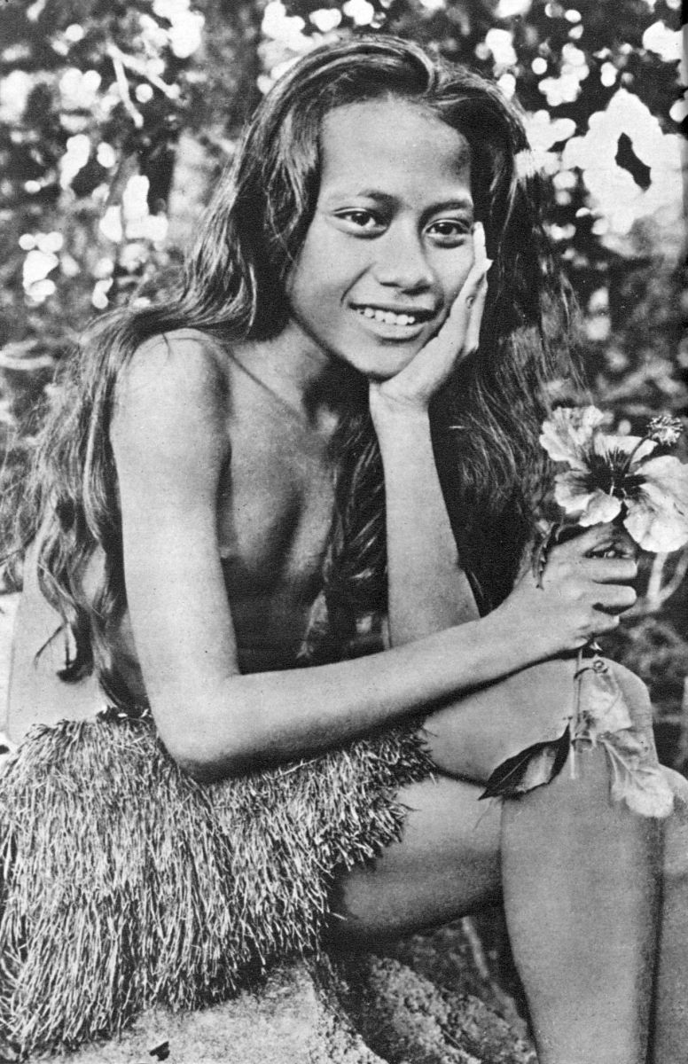 girl with long hair sitting in grass skirt posing for picture