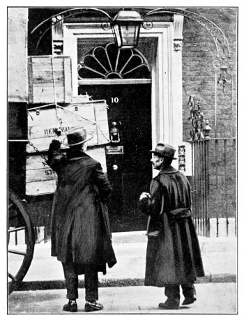crates loaded on a cart in front of 10 Downing Street with 2 men in coats and hats supervising