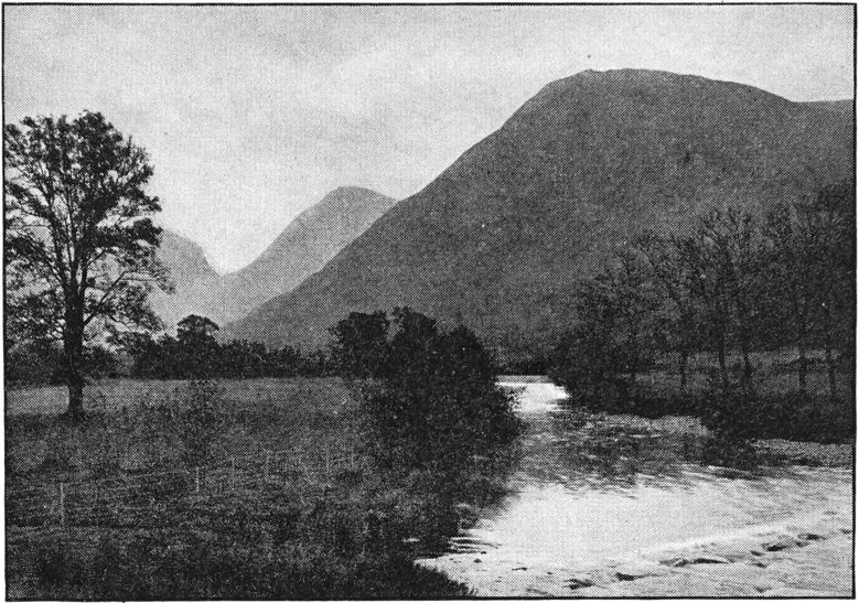 Photo of river and pasture in rugged terrain.