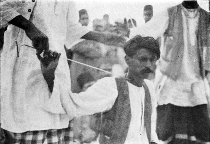 man with long skewer piercing his neck