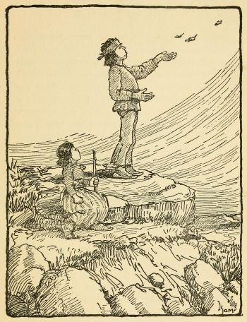 Indian boy standing on rocktop blowing feathers into the wind while seated girl watches