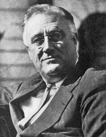 a seated Roosevelt wearing specs