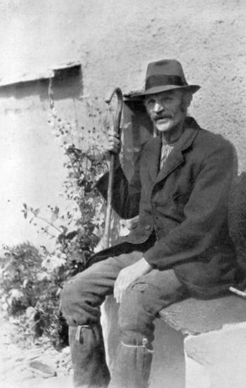 farmer sitting with cane wearing hat and boots
