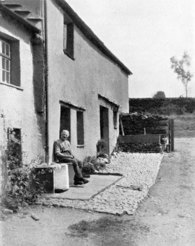 man sitting in front of farmhouse
