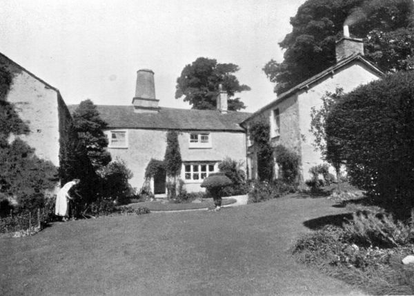 lady in a garden in front of 3-sided farmhouse