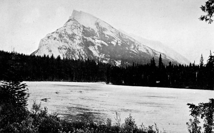 a large river flows past a tall, sharp mountain