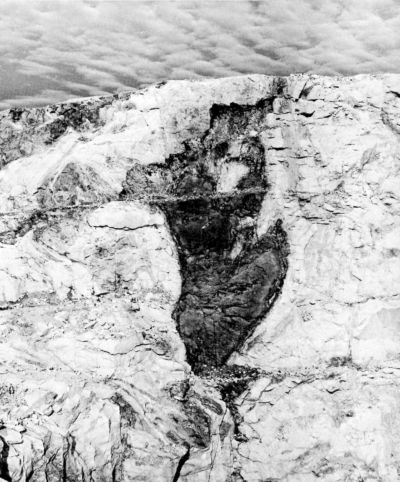 large dark deposit inside light marble in a quarry wall