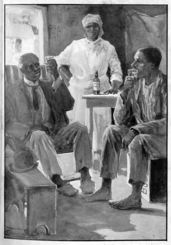 two men sitting with raised glasses in their hands with a woman standing behind them and the table with the bottle