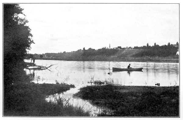 man fishing in boat with Goderich city across lake