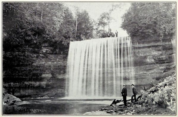 2 men at base of falls looking up at falls