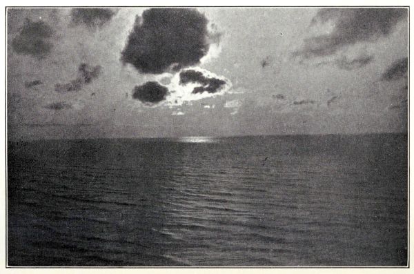 moon behind clouds reflecting on water