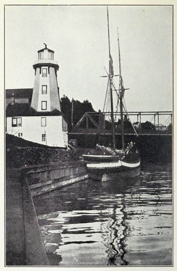 lighthouse and two-masted boat in harbour
