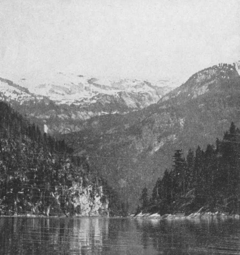 Photo of high, snow-capped mountains surrounding a small inlet.