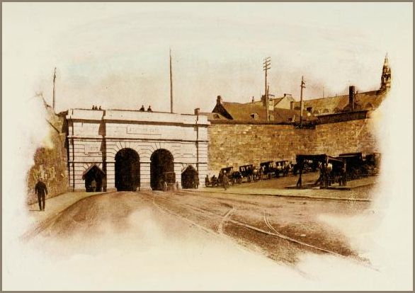 Image shows a massive stone gateway with three arches opening onto a busy street lined with horse-drawn carriages. In the background are rooftops and telegraph poles.